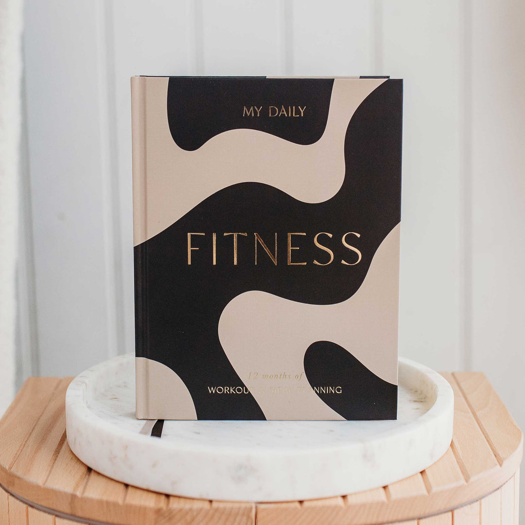 Daily workout planner open on a table with pen and water bottle nearby