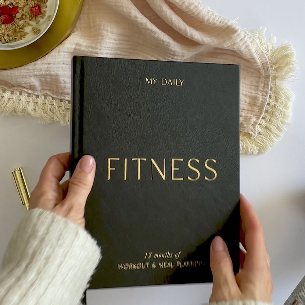 Flat lay of training logbook with dumbbells and protein shaker