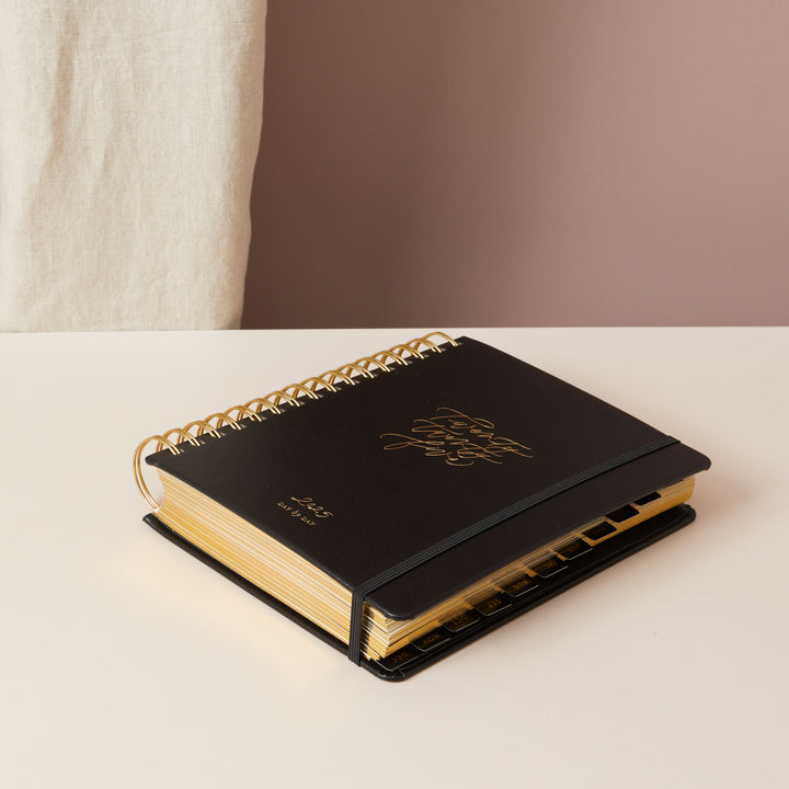 2025 daily diary in black vegan leather with gold foil accents on the cover, offering both style and functionality for everyday use.