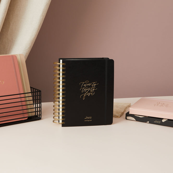 2025 daily diary with a chic black vegan leather cover and gold foil details, offering a blend of functionality and beauty.