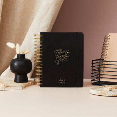 2025 daily planner in black vegan leather with gold detailing on the cover, designed for elegant and organised planning.