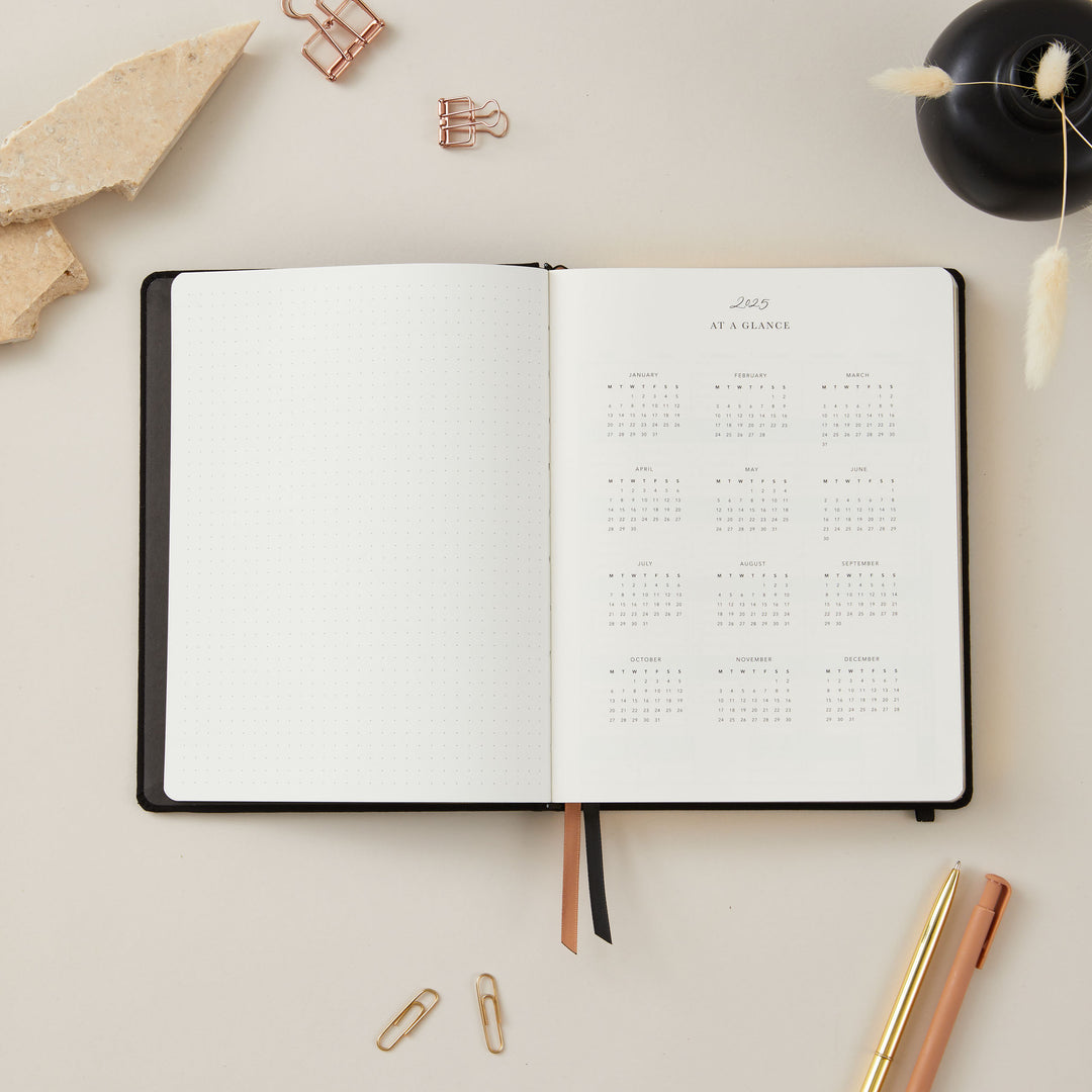 A 2025 diary open to a page displaying a yearly overview, featuring a clean and organised layout with all 12 months visible at a glance.