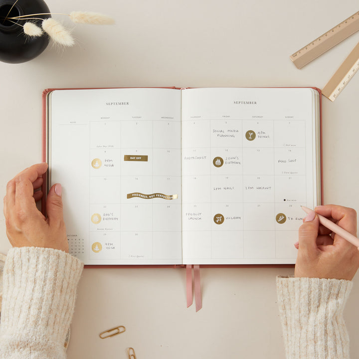 Clay vegan leather 2025 planner with gold details, featuring equal space for time-blocking each day, to-do lists, and pages for notes, monthly goals, and budgeting.