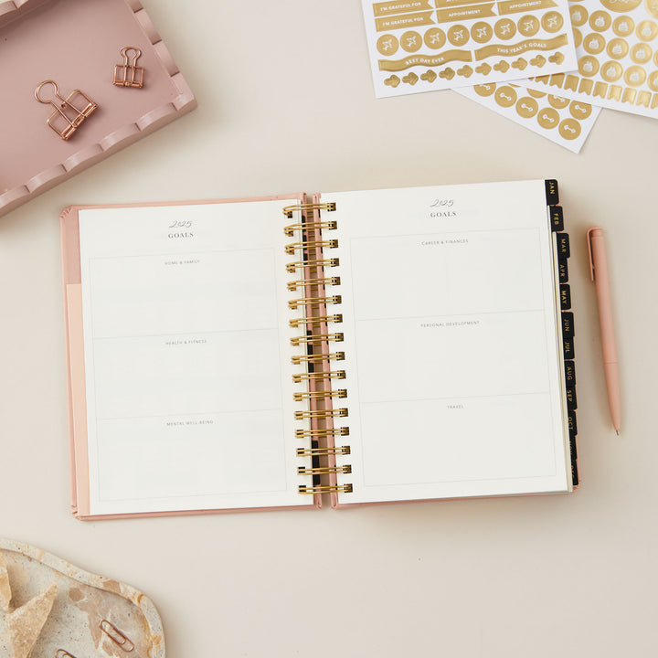 2025 planner in pink, with day-to-view pages that include today's priorities, a daily schedule with time blocking, to-do list, notes section, and meal plan.