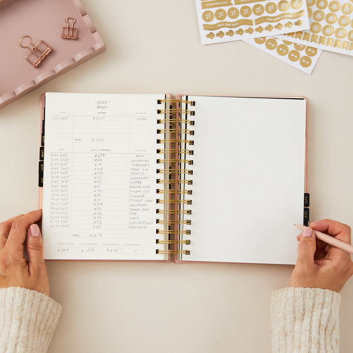 2025 planner with a pink cover, offering day-to-view pages with dedicated sections for today's priorities, a time-blocked schedule, to-do list, and meal planning.
