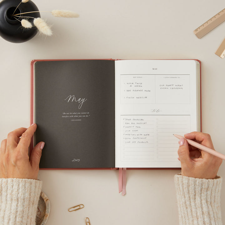 Stylish 2025 planner with a clay vegan leather cover and gold accents, offering weekly time-blocking, to-do lists, and sections for notes and monthly goal-setting.