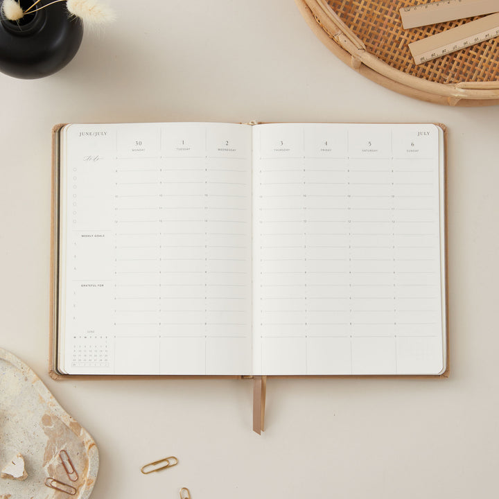 Ivory fabric 2025 planner with gold details, offering weekly time-blocking with equal space for each day, along with to-do lists, notes, and monthly goals and budgeting sections.