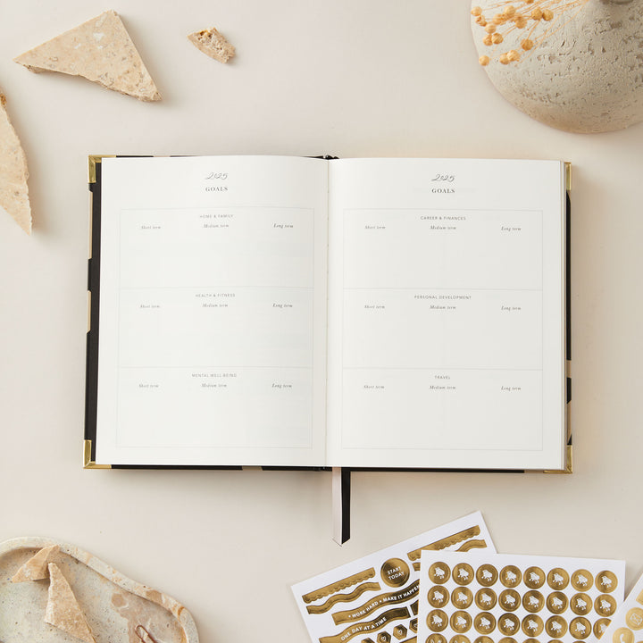 Chic 2025 weekly planner with a minimalist floral design, gold foil cover, and gold edging, offering weekly pages with time blocking, to-do lists, and space for notes.