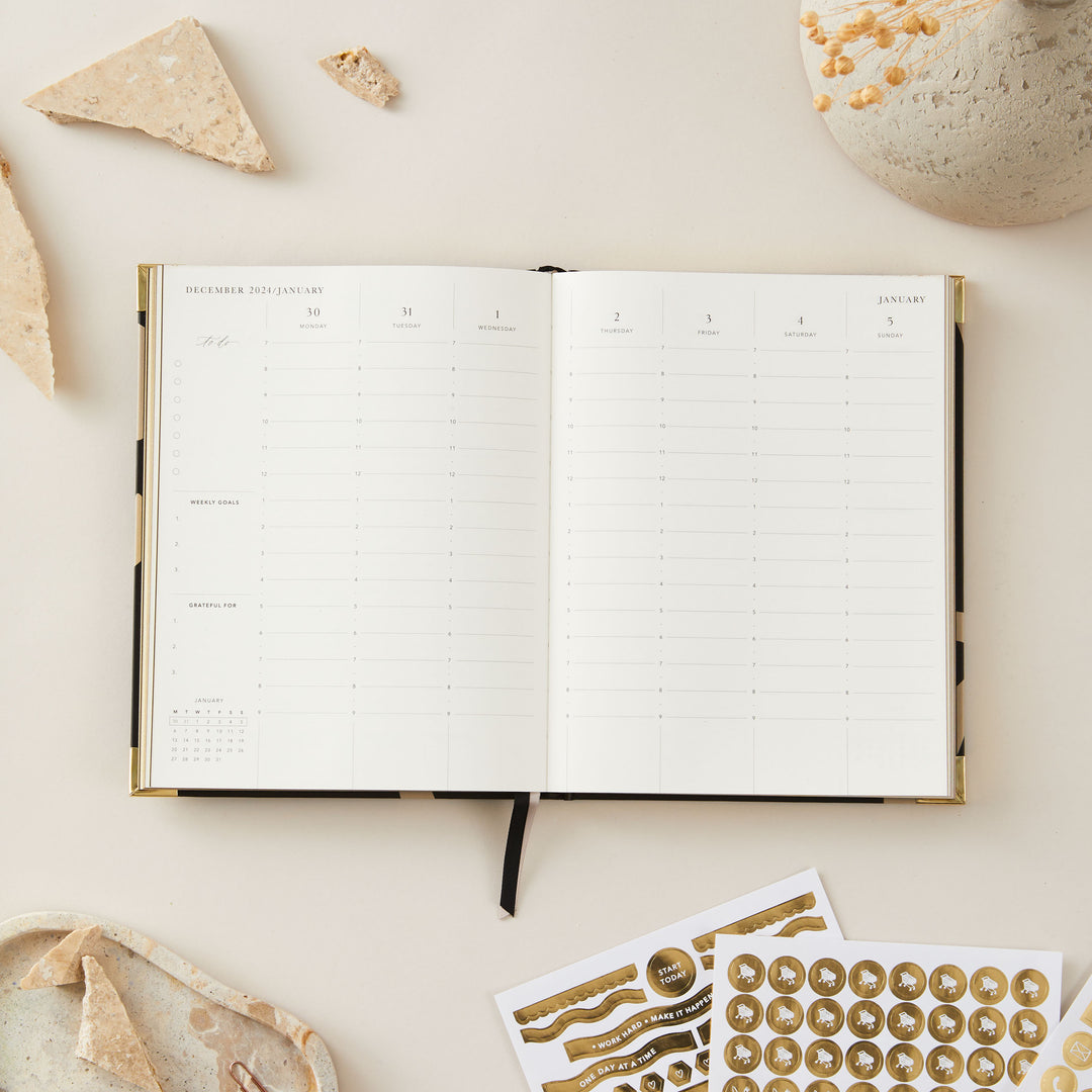 Minimalist floral 2025 weekly planner with a gold foil cover and gold edging, offering week-to-view pages, time blocking, to-do lists, and sections for notes.