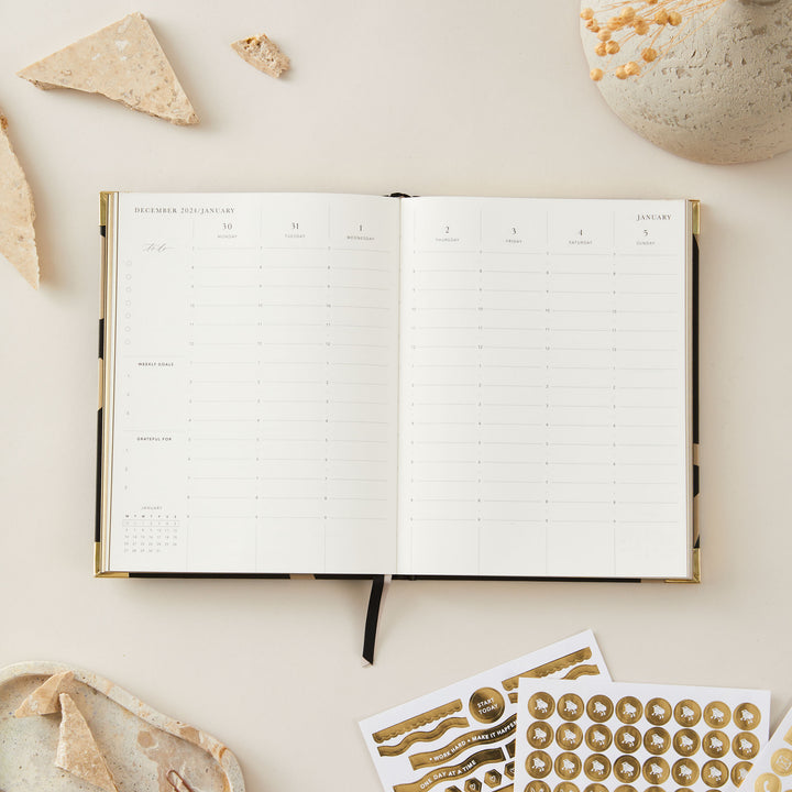 Minimalist floral 2025 weekly planner with a gold foil cover and gold edging, offering week-to-view pages, time blocking, to-do lists, and sections for notes.