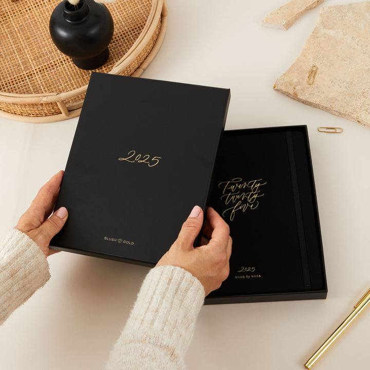 2025 weekly planner with a soft black vegan leather cover and gold details, featuring time-blocking with equal space for each day, to-do lists, notes, and monthly goals and budget pages.
