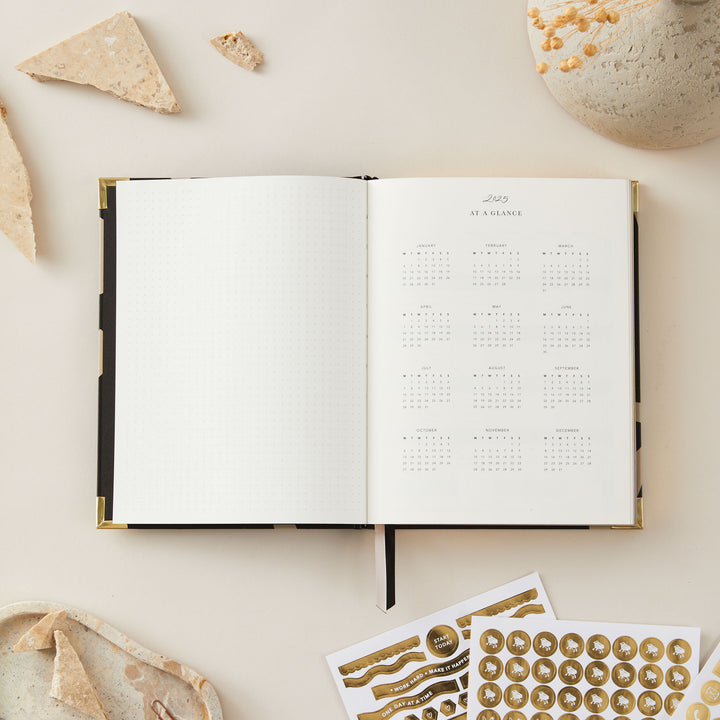 2025 weekly planner with a minimalist floral design, featuring a gold foil cover and gold edging, with week-to-view pages, time blocking, to-do lists, and space for notes.