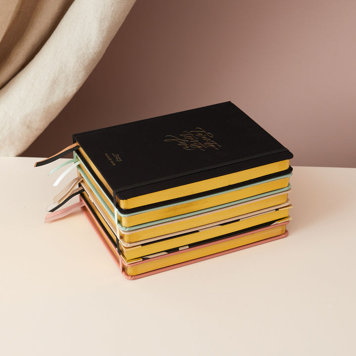 2025 weekly planner with a minimalist cover in gold foil and gold edging, offering time-blocking layouts, to-do lists, notes, and monthly budget sections.