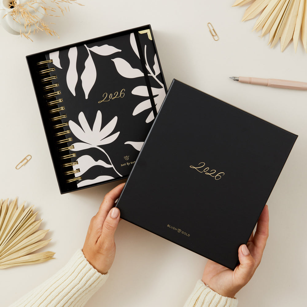 Planners with '2026' on a light surface with decorative elements and gift box.