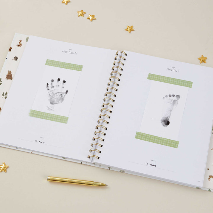 Open woodland baby record book showing guided memory pages.