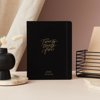 A black luxury 2025 diary with a cloth cover, adorned with gold foil details