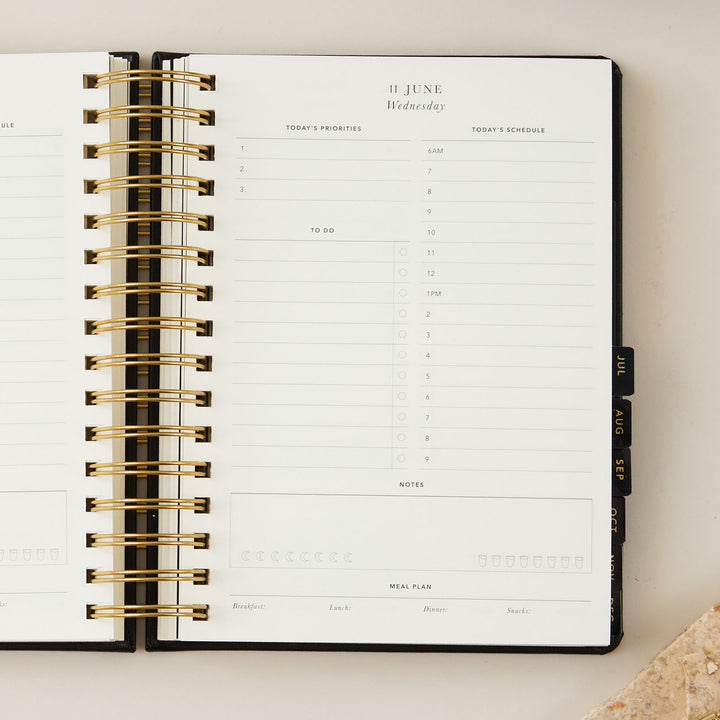 Elegant black vegan leather 2025 daily diary featuring luxurious gold foil details on the cover, blending beauty with practicality.