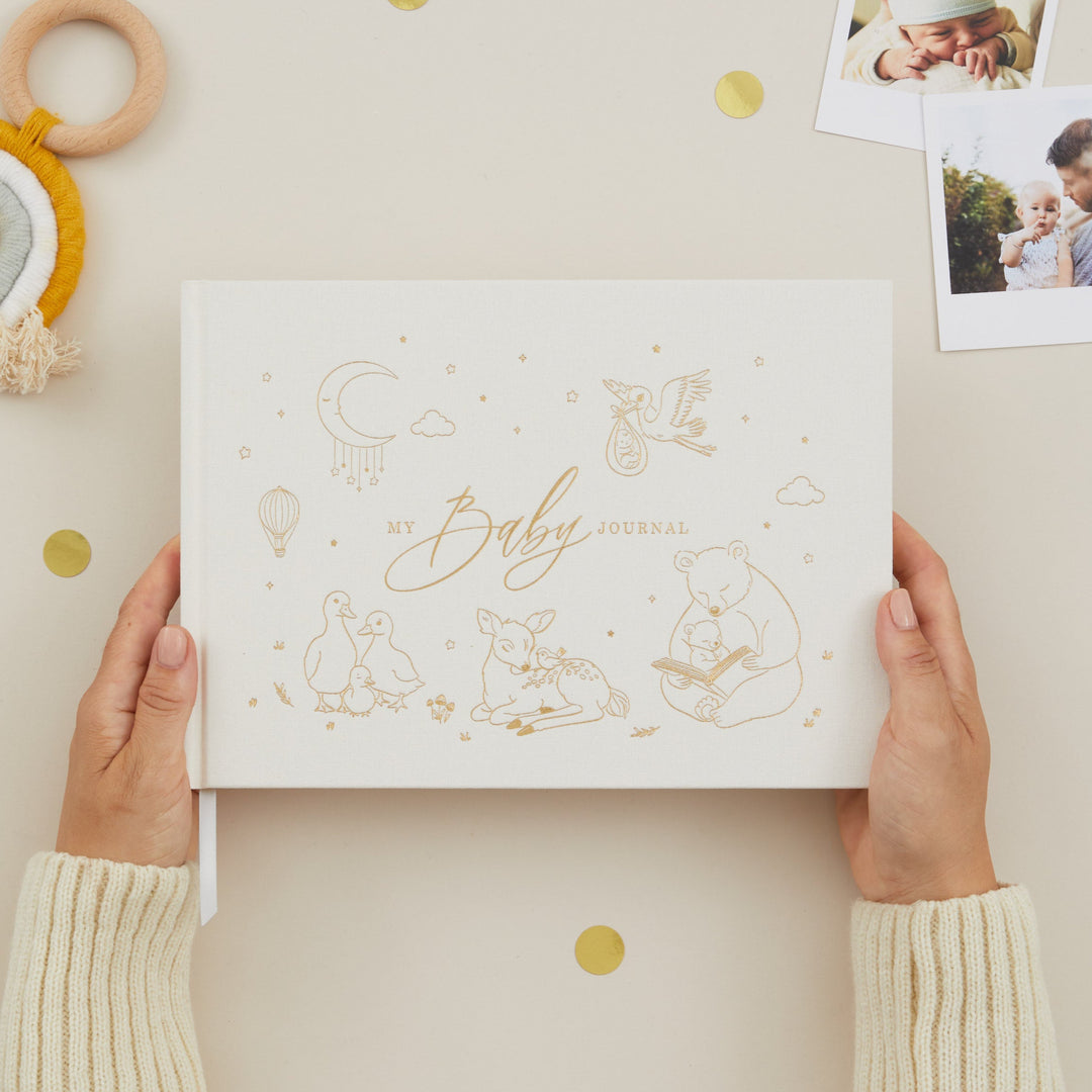 Person holding a baby journal with decorative elements on a light background
