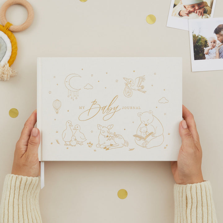 Person holding a baby journal with decorative elements on a light background