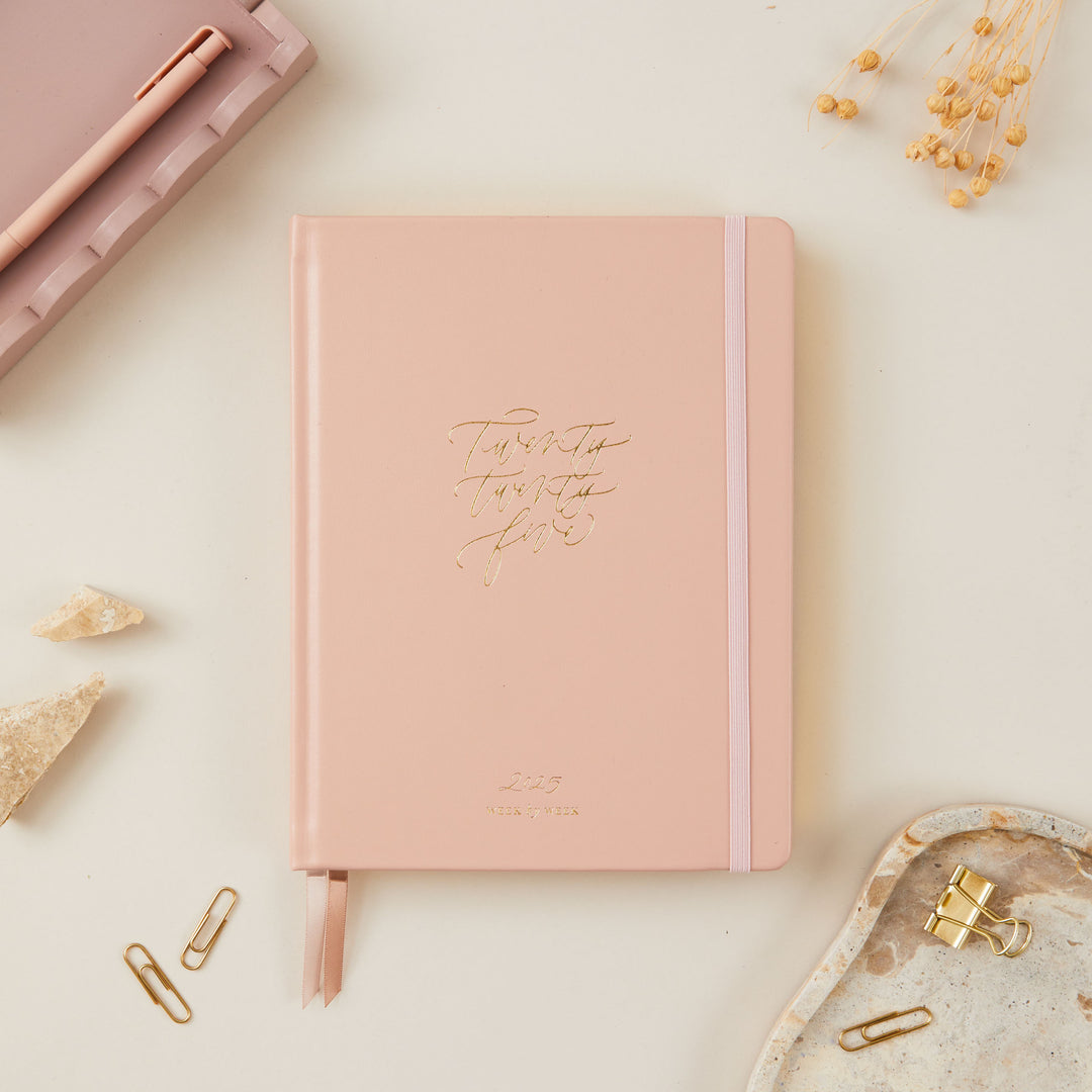 Soft pink vegan leather 2025 planner with gold details, providing equal space for daily time-blocking, to-do lists, note pages, and monthly goals and budgeting.