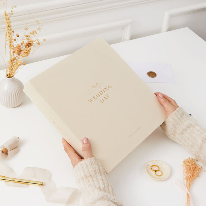 Classic wedding photo album with a cloth ivory cover, gold accents, and ivory pages, the perfect present for newlyweds.