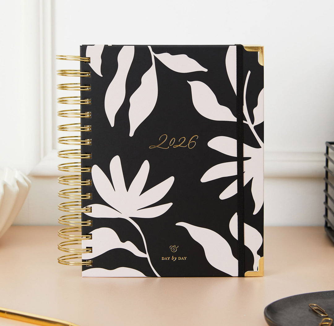 Black notebook with white leaf pattern and '2026' on a light surface
