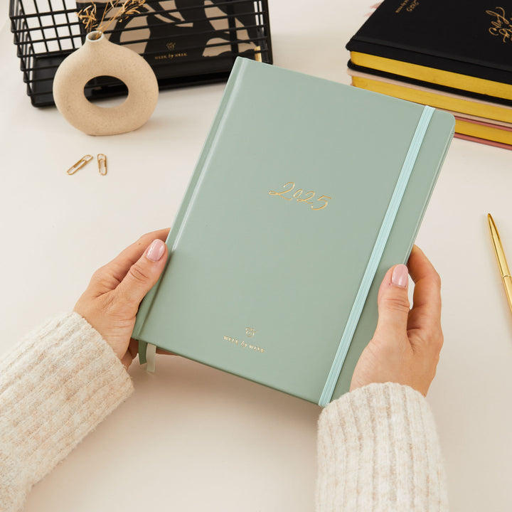 2025 weekly planner with a sage green vegan leather cover and gold details, offering equal space for daily time-blocking, to-do lists, notes, and monthly goals and budget pages.