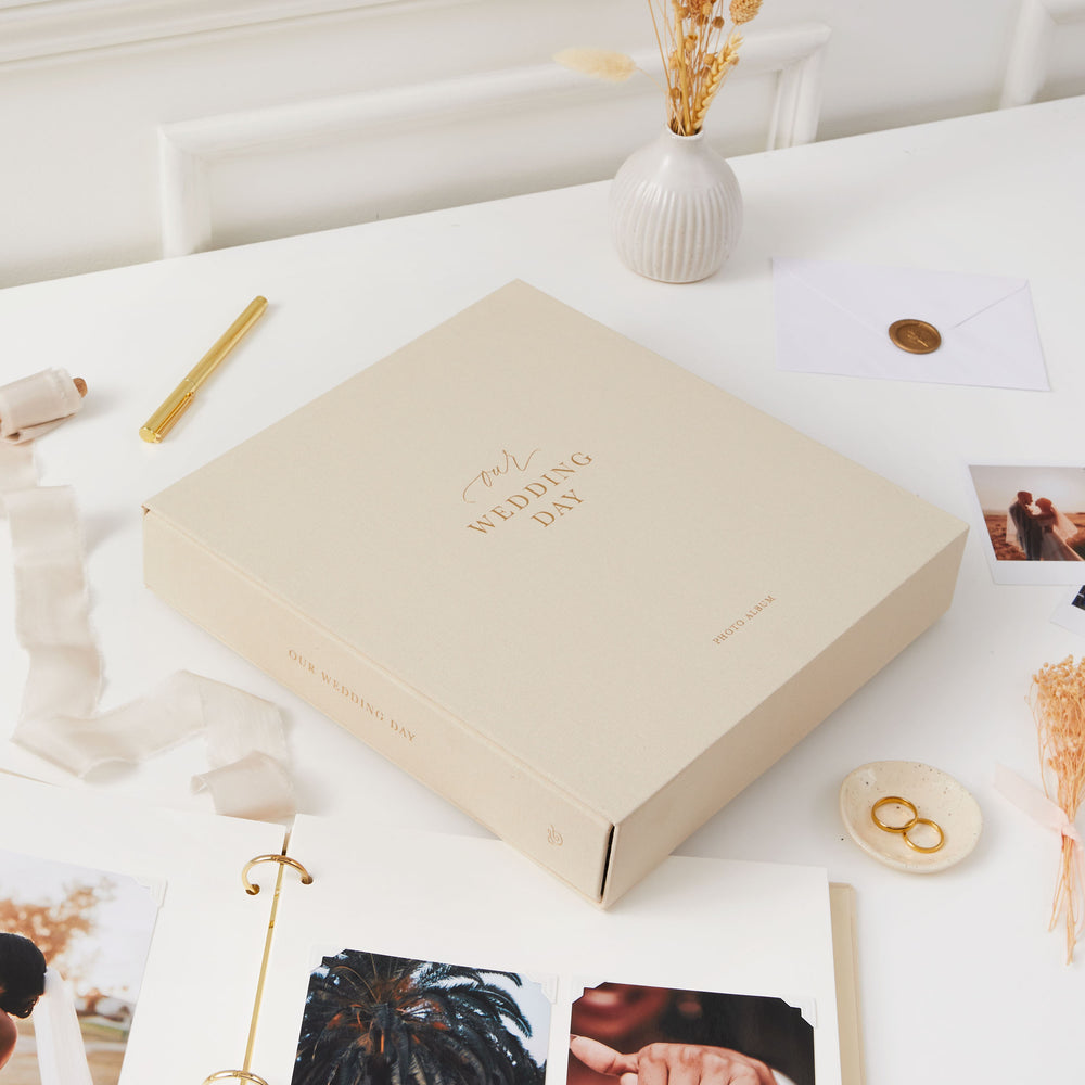 Elegant blank wedding photo album with a cloth ivory cover, gold details, and a matching slipcase, perfect for newlyweds.