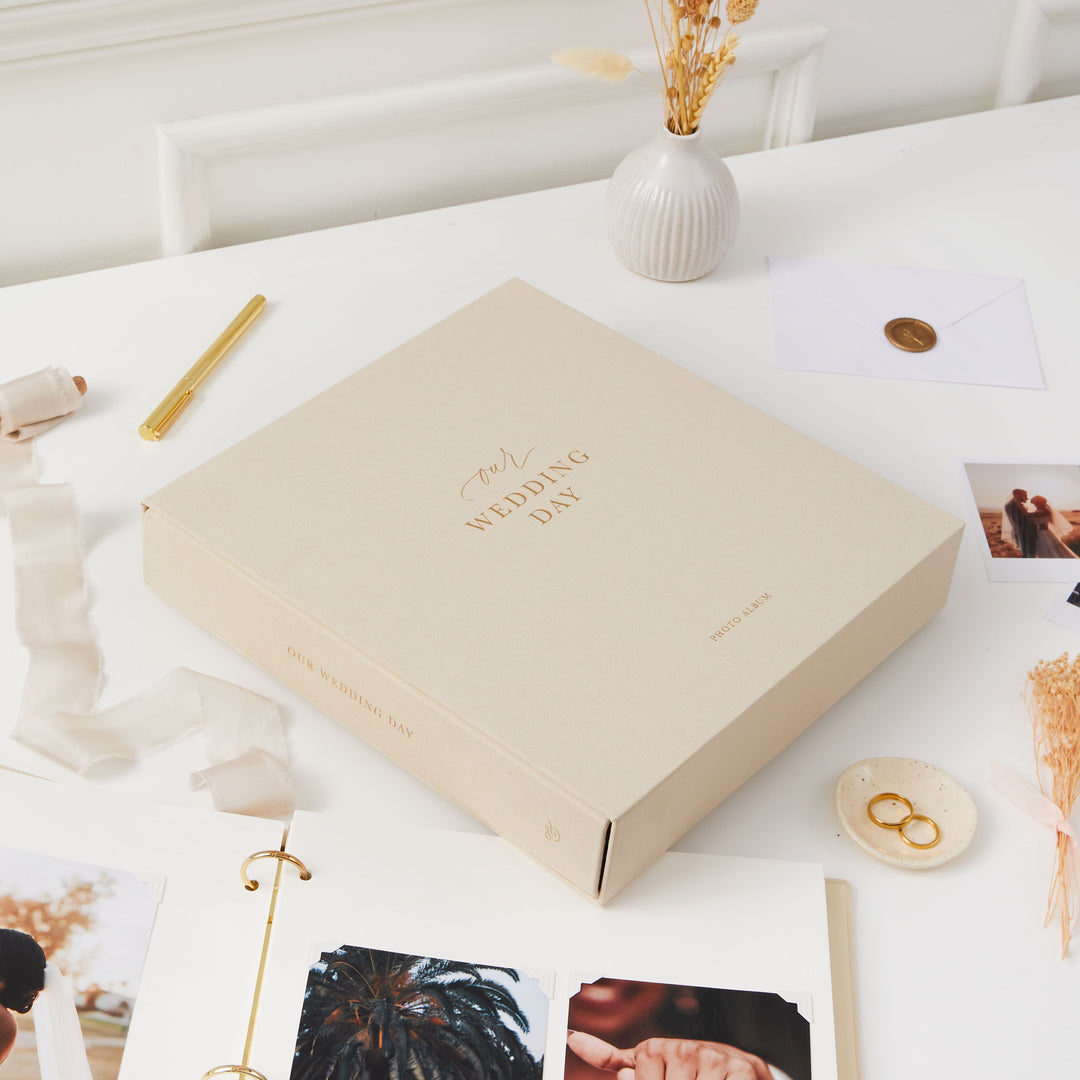 Elegant blank wedding photo album with a cloth ivory cover, gold details, and a matching slipcase, perfect for newlyweds.