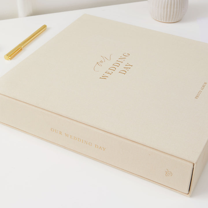 Ivory cloth wedding photo album with gold embellishments and blank pages, a sophisticated present for newlyweds.