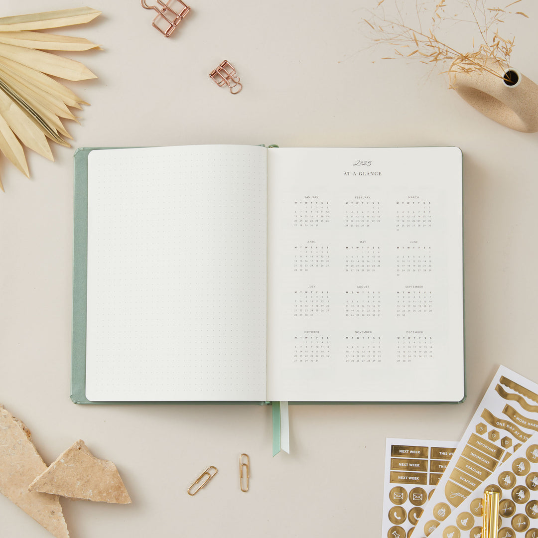 2025 planner with a sage green vegan leather cover and gold accents, featuring equal space for time-blocking each day, to-do lists, and monthly budget and goal pages.