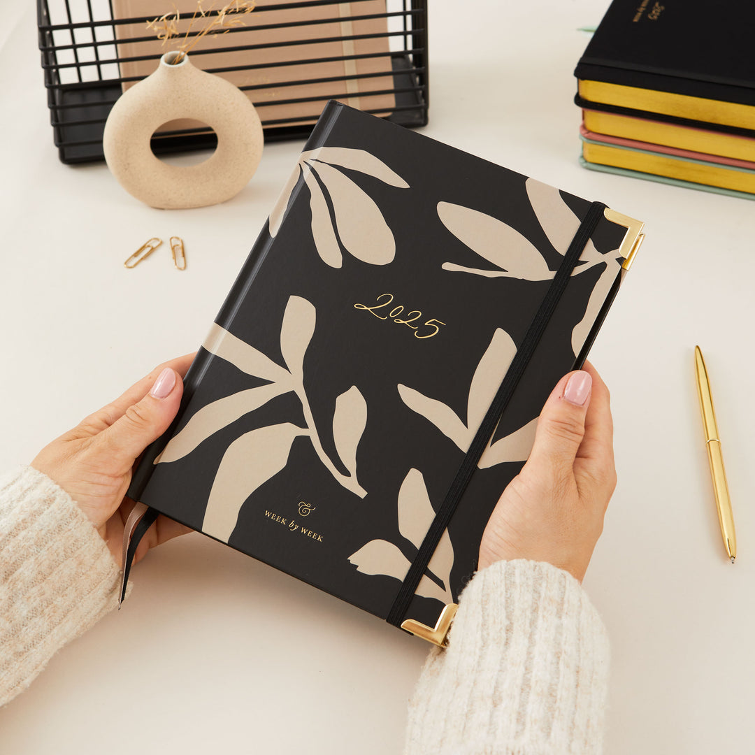 Sleek 2025 weekly planner with a minimalist floral design, gold foil cover, and gold edging, including time-blocking, to-do lists, and space for notes.