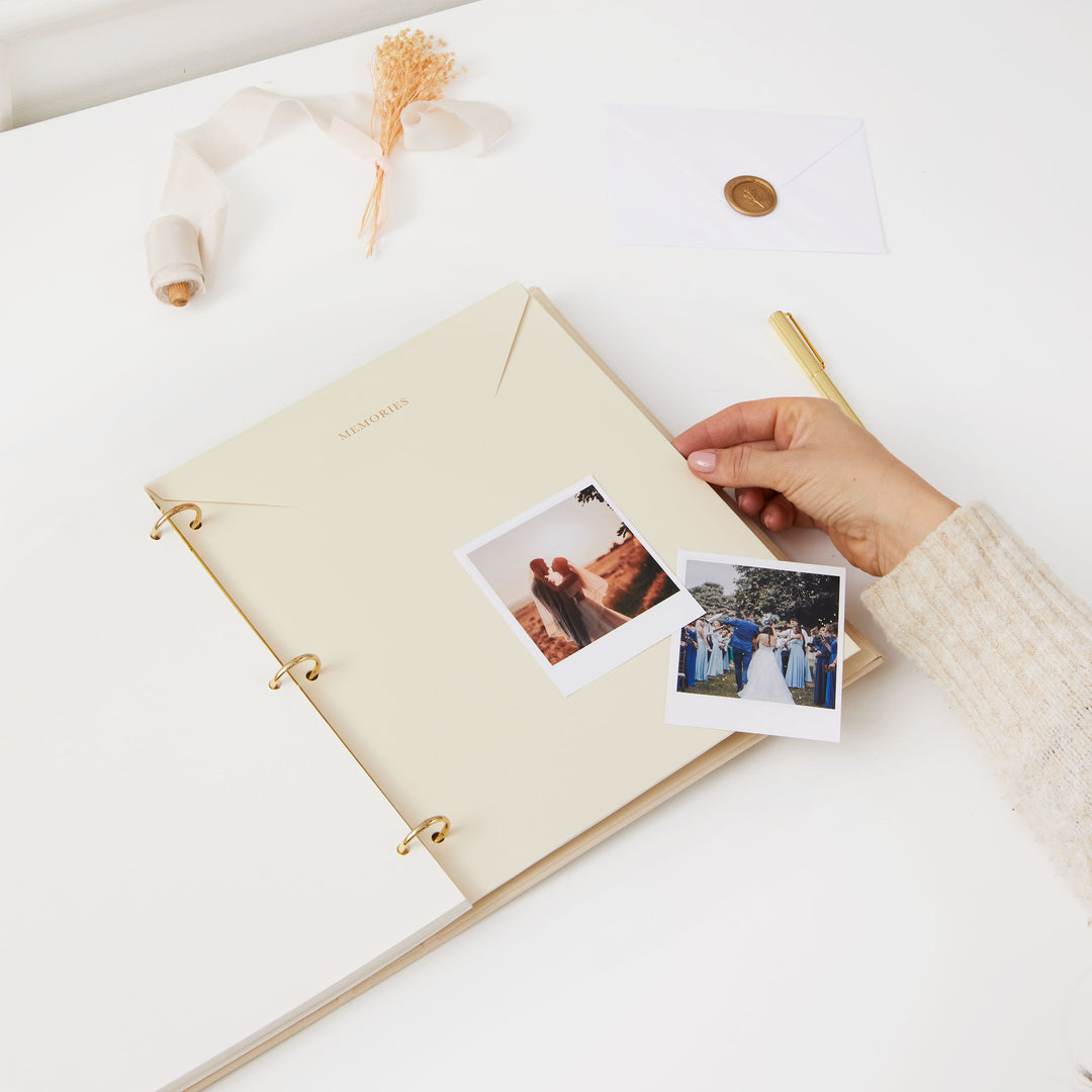 Minimalist wedding photo album with an ivory cloth cover, gold details, and ivory pages, perfect for preserving memories.