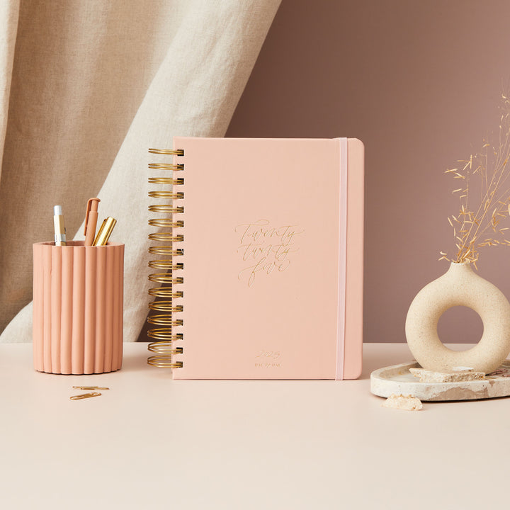 Pink Daily 2025 ring-bound planner featuring a minimalist design with gold foil detailing on the cover for an elegant look.