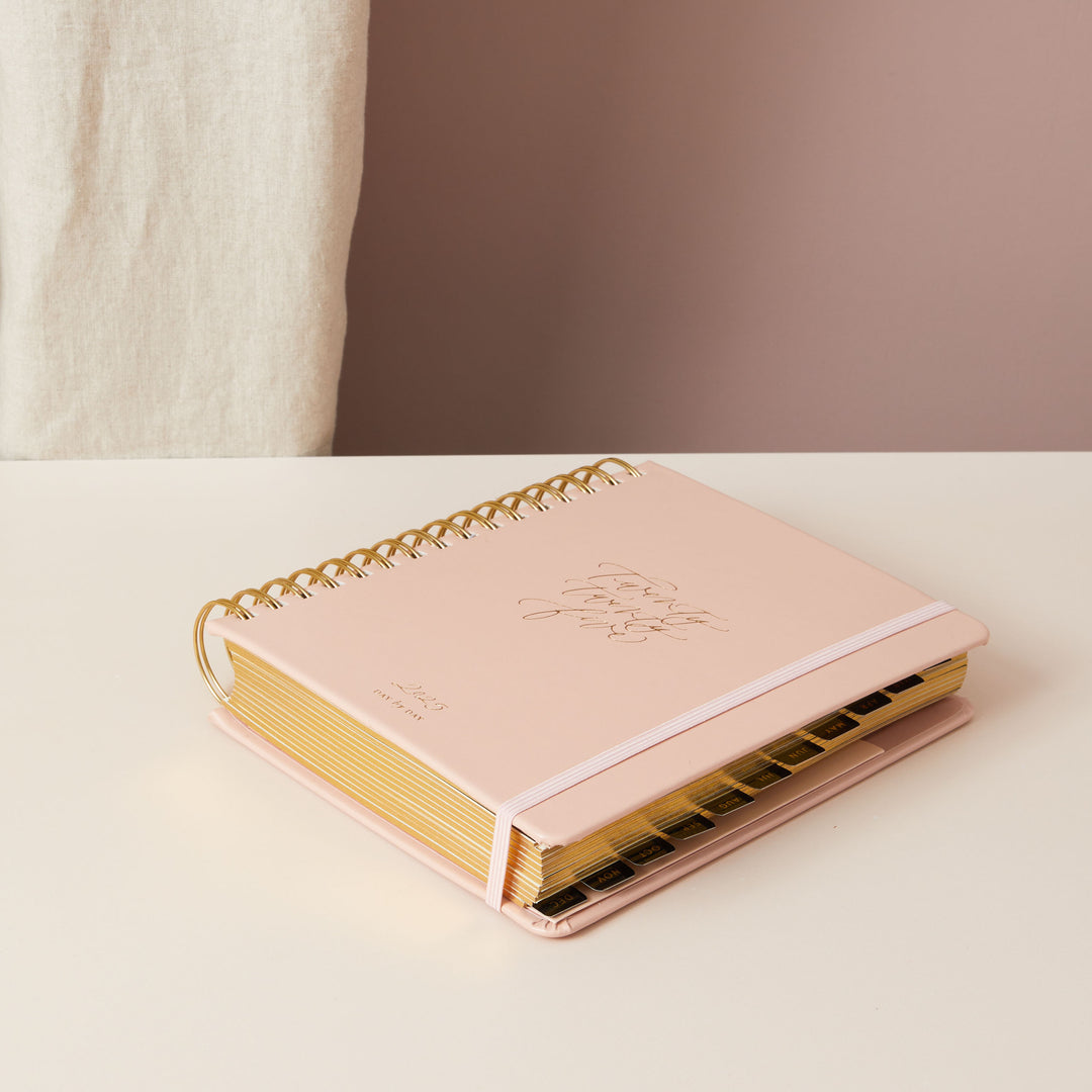 Pink day-to-page 2025 ring-bound planner featuring monthly tabs for easy navigation and organisation.