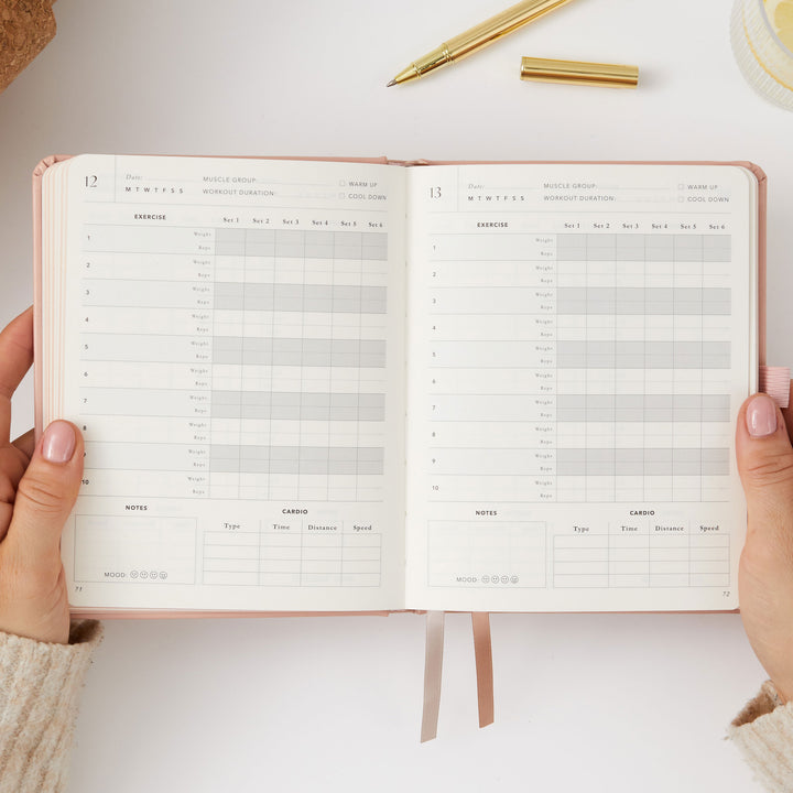 Pink fitness journal for logging sets, reps, and weights