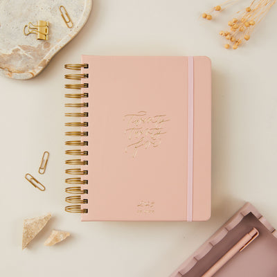 Pink vegan leather ring-bound daily planner with a smooth cover and gold accents for an elegant and functional design.