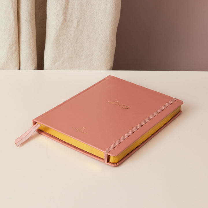 Rust vegan leather 2025 weekly planner with gold accents, offering equal space for daily time-blocking, to-do lists, notes, and monthly goals and budgeting.