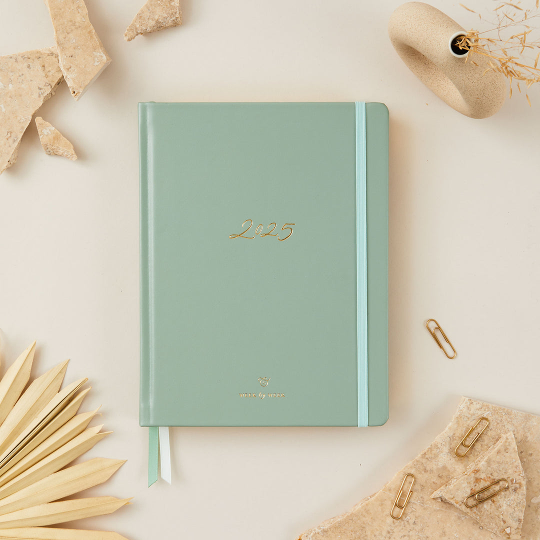 2025 weekly planner with a sage green vegan leather cover and gold details, featuring time-blocking with equal space for each day, to-do lists, notes, and monthly goals and budget pages.