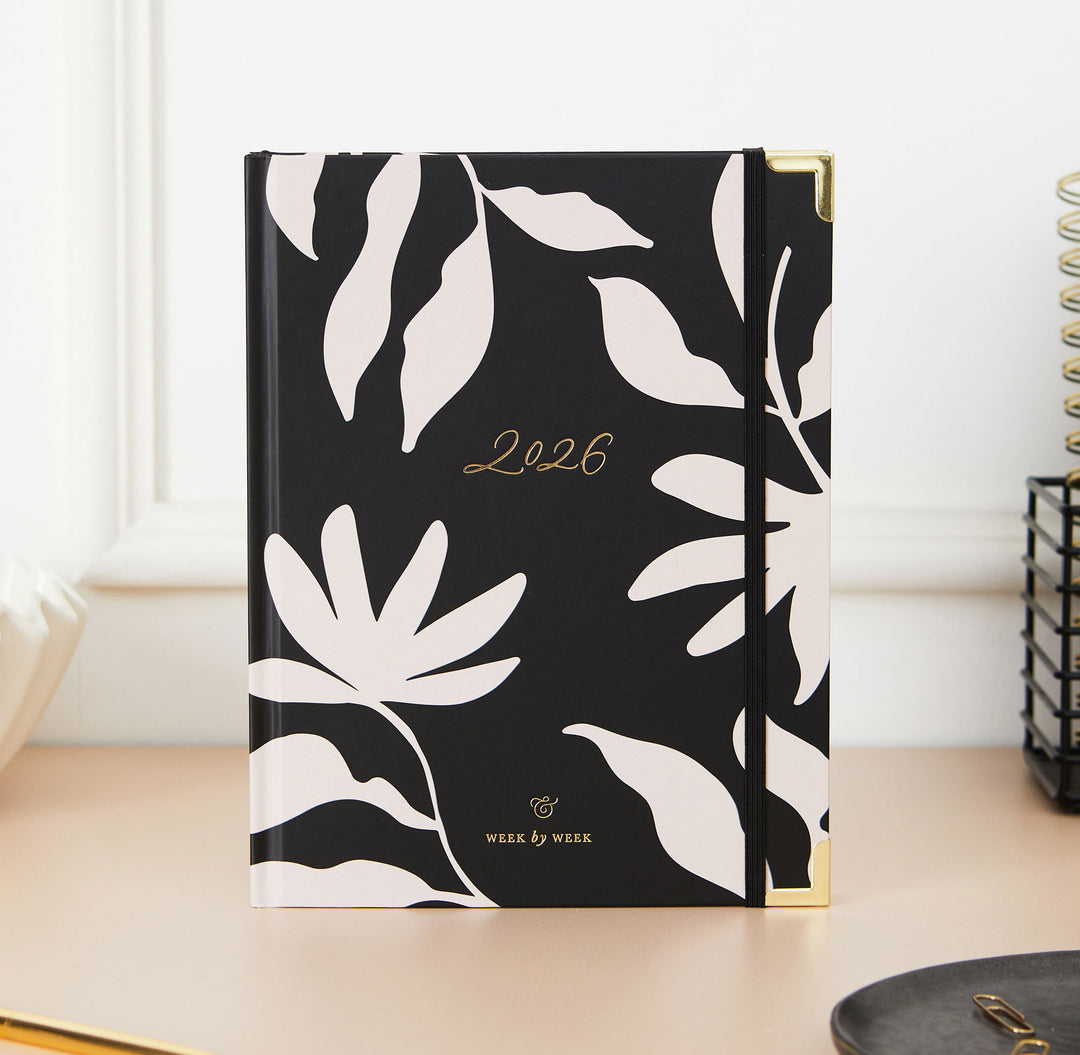 Black notebook with white leaf patterns and '2026' on a light surface