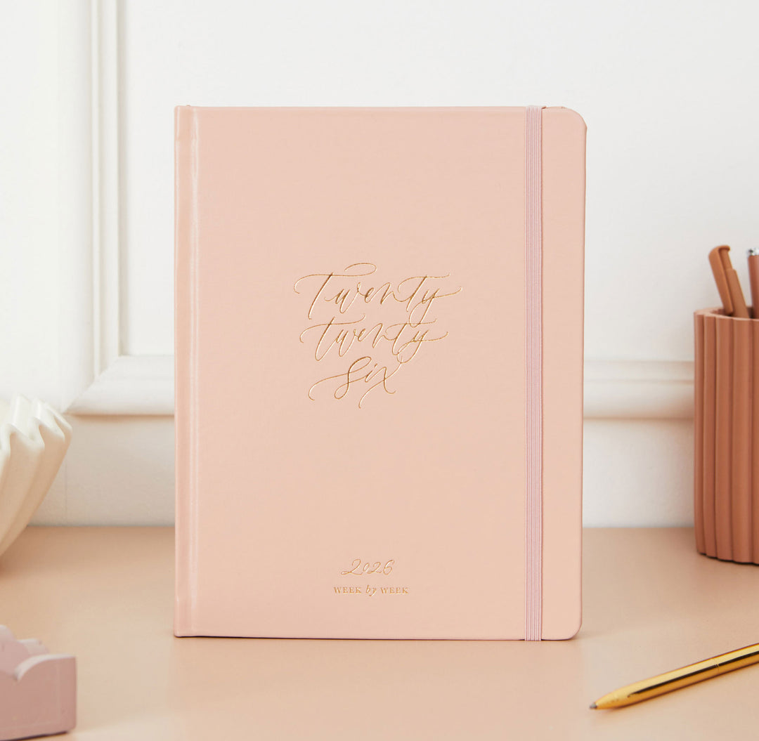 Pink notebook with 'Twenty Twenty Six' on a desk