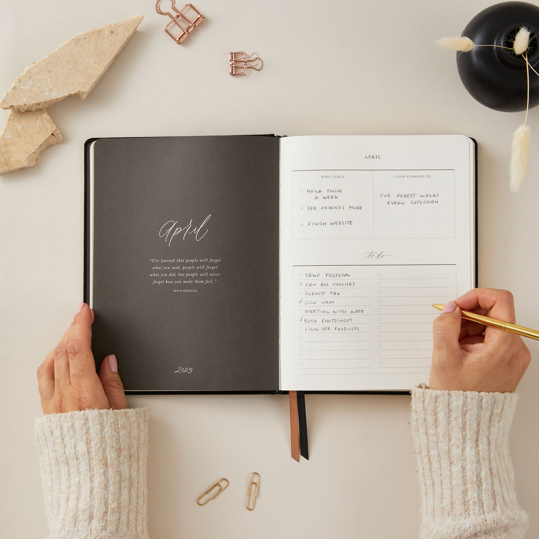 Elegant 2025 weekly planner with a soft black vegan leather cover and gold details, including time-blocking for each day, to-do lists, and sections for monthly goals and budget tracking.