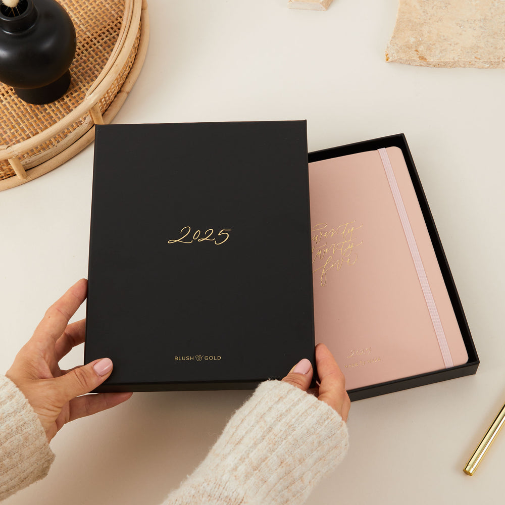 Elegant 2025 weekly planner with a soft pink vegan leather cover and gold details, including time-blocking for each day, to-do lists, and sections for monthly goals and budget tracking.