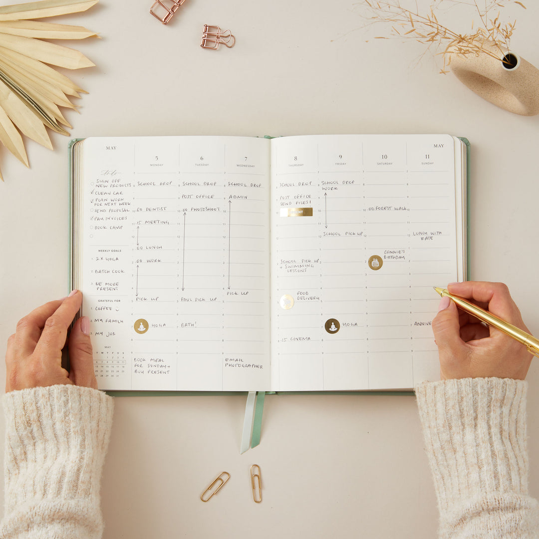 Sage green vegan leather-covered 2025 planner with gold details, designed with weekly time-blocking, to-do lists, note space, and sections for monthly goals and budgeting.