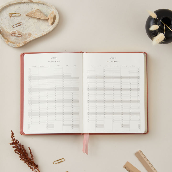 Elegant 2025 planner with a clay vegan leather cover and gold accents, featuring time-blocking, to-do lists, and sections for monthly goals and budget planning.