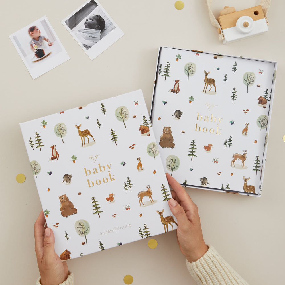 Two baby books with animal patterns held by a hand on a light background.