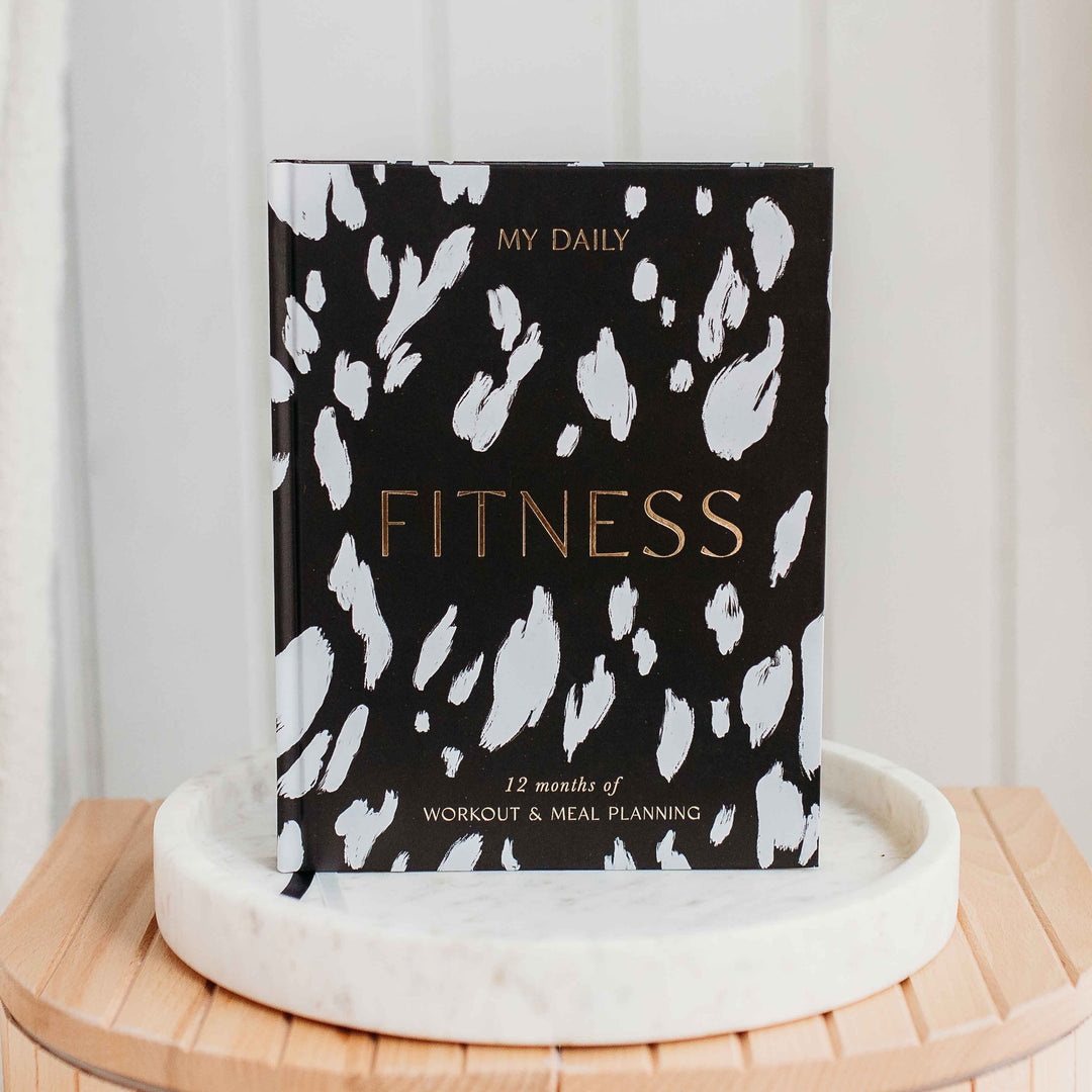 Exercise log and nutrition tracker open on wooden desk