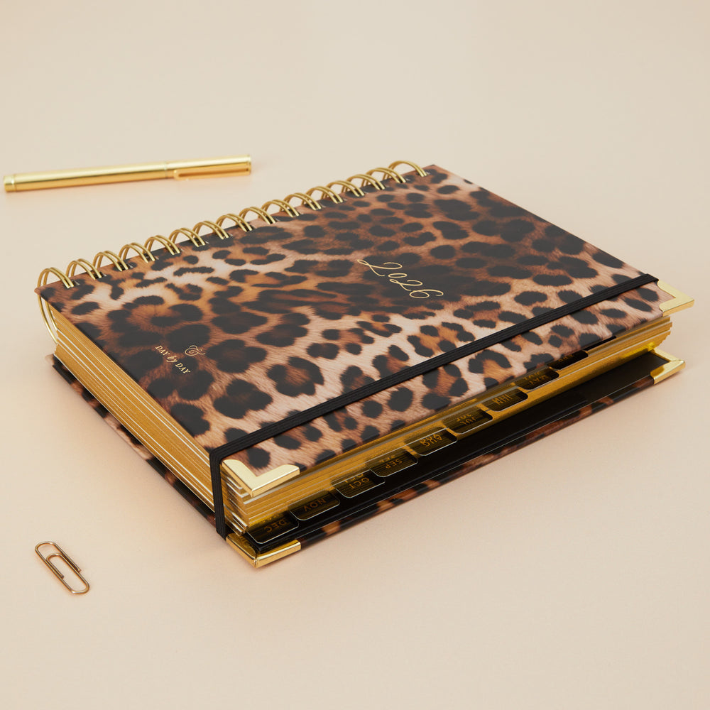 Leopard print planner with gold accents on a beige background