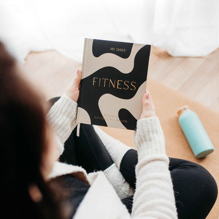 Close-up of hand writing in daily workout planner