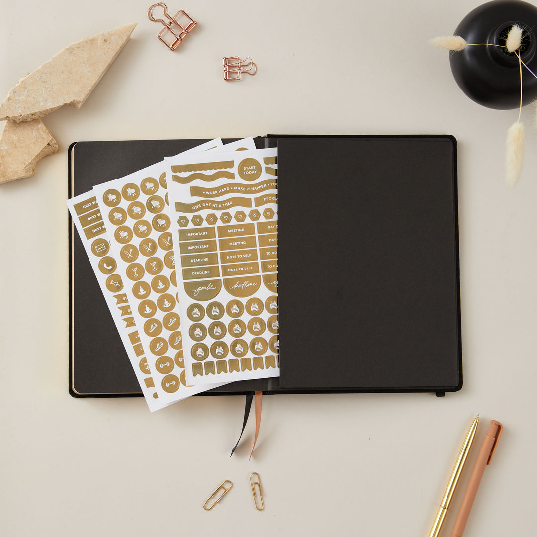 Soft black vegan leather 2025 weekly planner with gold accents, offering equal space for daily time-blocking, to-do lists, notes, and monthly goals and budgeting.